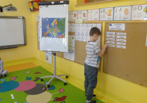 Chłopiec przyczepia na tablicy nazwę kraju należącego do Unii Europejskiej.